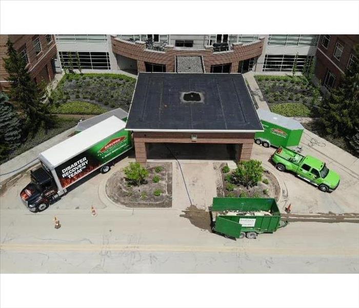 Fleet of SERVPRO vehicles outside commercial buildings.